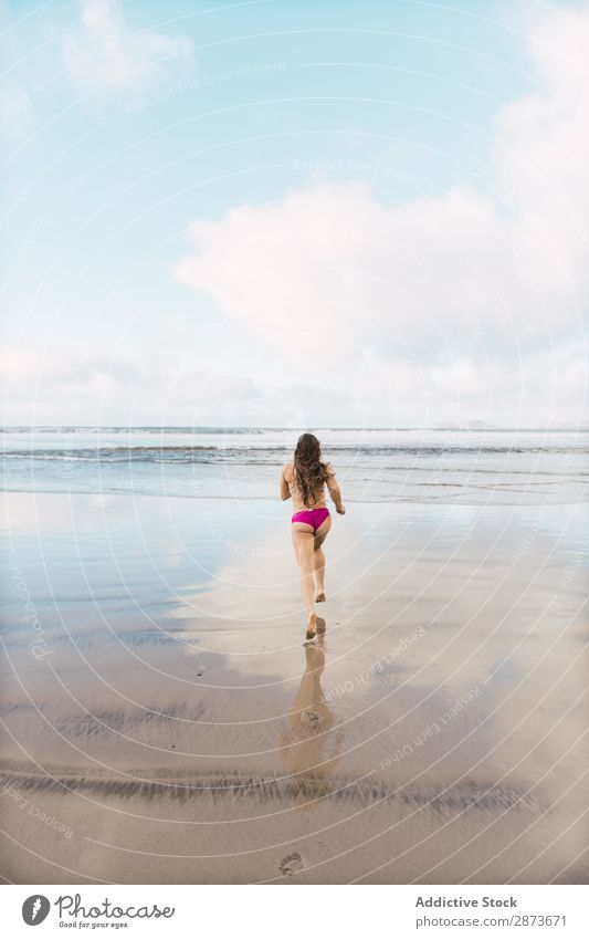 Frau in Badebekleidung, die in Meeresnähe läuft. rennen Wegsehen Wellen Barfuß Sand nass üben dünn Fitness Training Sport Wasser Freude Joggen Dame Bikini