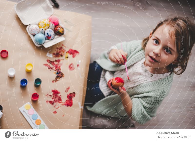 Mädchen mit Pinsel färbt Hühnereier am Tisch im Zimmer. Ostern Ei Bürste Raum Sofa Färbung lustig Kind Hähnchen Container Gemälde Frühling Kulisse