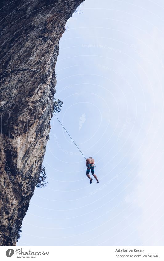 Anonymer Kletterer, der auf einer Klippe herumläuft. Aufsteiger erhängen Seil extrem Himmel blau Berge u. Gebirge Felsen Sport Herausforderung Aktion Erfolg