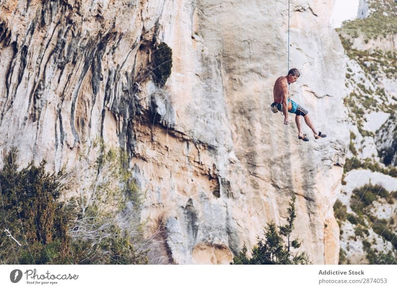 Anonymer Kletterer, der auf einer Klippe herumläuft. Aufsteiger erhängen Seil extrem Himmel blau Berge u. Gebirge Felsen Sport Herausforderung Aktion Erfolg