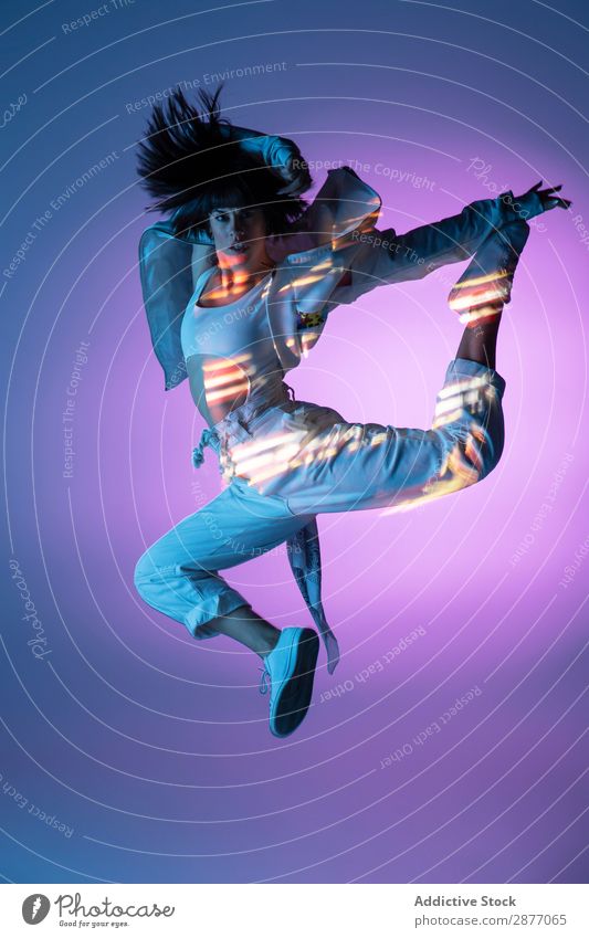 Energetische Tänzerin, die springt und auf die Kamera schaut. Frau springen Bewegung Licht Jugendliche modern Stil Aktion Energie Kraft Zeitgenosse trendy Pose