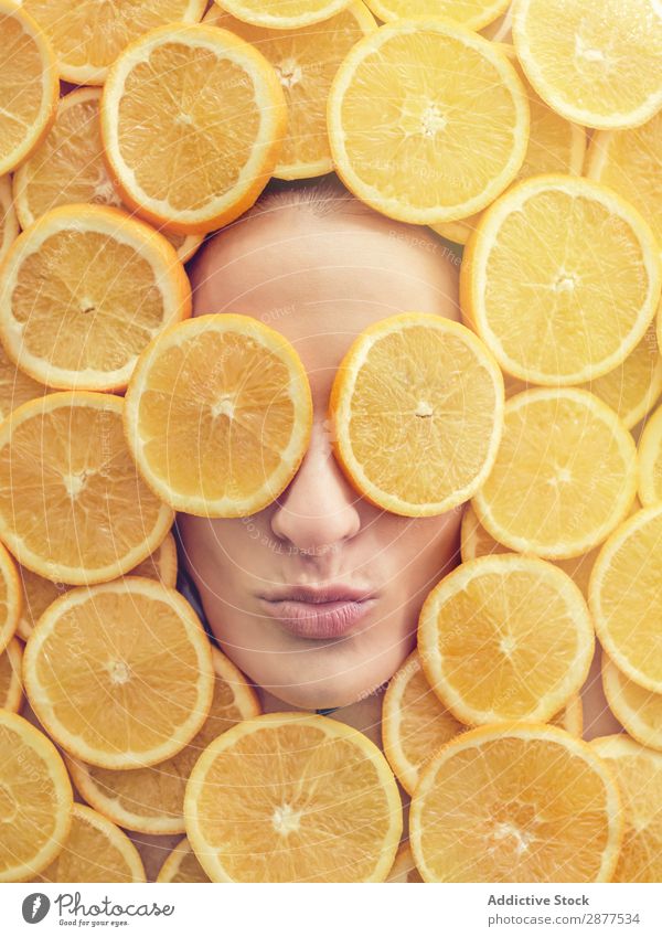 Lächelnde Frau zwischen den Orangenscheiben Gesicht Scheibe frisch Entwurf Glück Jugendliche schön Beautyfotografie Gesundheit attraktiv Frucht Fürsorge Freude