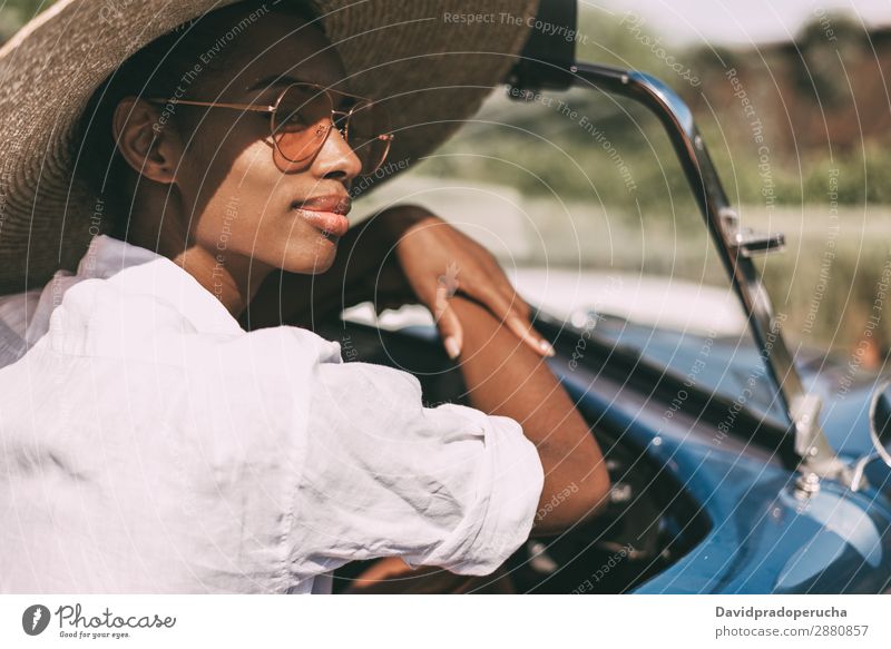 Schwarze Frau fährt ein Oldtimer-Cabriolet. PKW fahren rechtes Lenkrad urwüchsig Glück Straße schwarz vereinigtes königreich Reichtum Wegsehen Strohhut