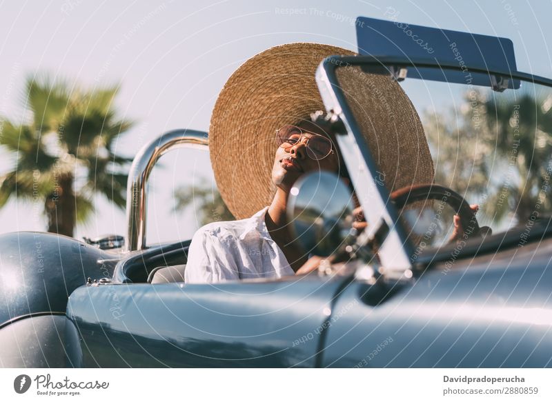 Schwarze Frau fährt ein Oldtimer-Cabriolet. PKW Glück fahren rechtes Lenkrad urwüchsig Straße schwarz vereinigtes königreich Reichtum Strohhut Sonnenbrille