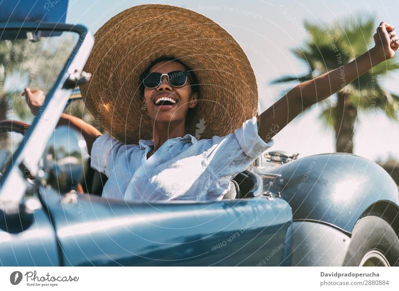 Schwarze Frau fährt ein Oldtimer-Cabriolet. PKW fahren urwüchsig Verkehr Straße schwarz Reichtum Wegsehen heiter Glück Lächeln altehrwürdig klassisch 60's schön