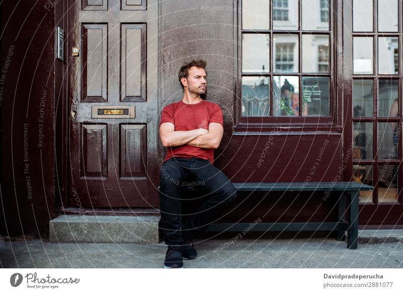 Mann sitzt auf einer Bank auf einem schönen kastanienbraunen Hintergrund. Kaukasier Gebäude Jugendliche Architektur altehrwürdig Nottinghill Dekor Straße sitzen