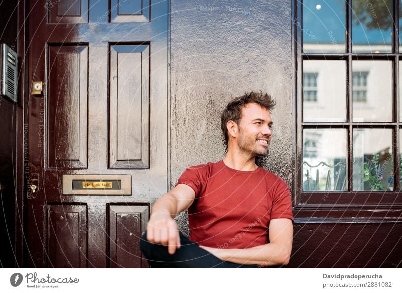Mann sitzt auf einer Bank auf einem schönen kastanienbraunen Hintergrund. heiter Kaukasier Gebäude Jugendliche Glück Architektur altehrwürdig Lächeln