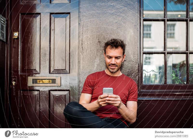 Mann sitzt auf einer Bank auf einem schönen kastanienbraunen Hintergrund. Handy Kaukasier heiter Gebäude Jugendliche Architektur Technik & Technologie