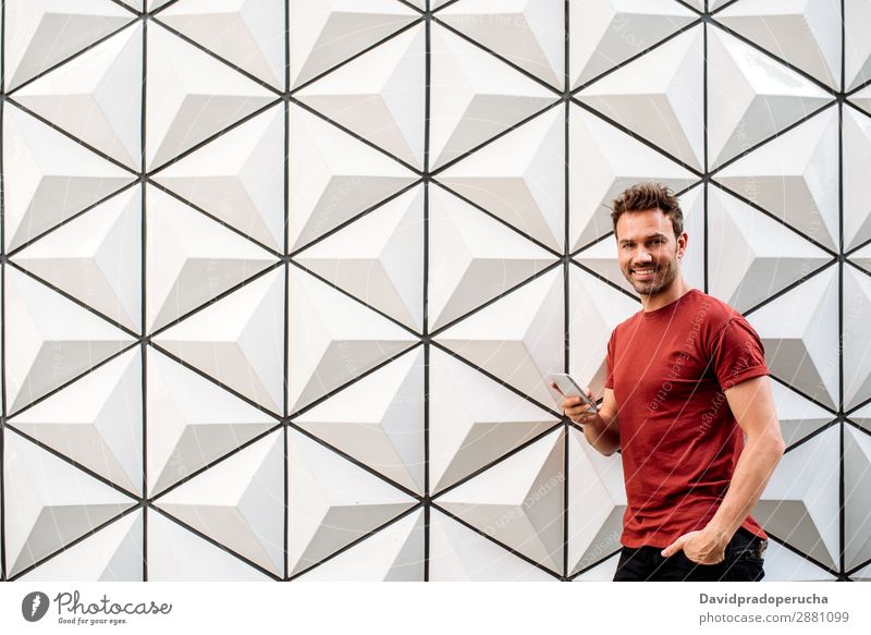 Mann mit Handy an der Wand gelehnt Architektur Kaukasier PDA Geometrie Porträt Hintergrundbild Technik & Technologie Jugendliche Zukunft Gebäude achteckig