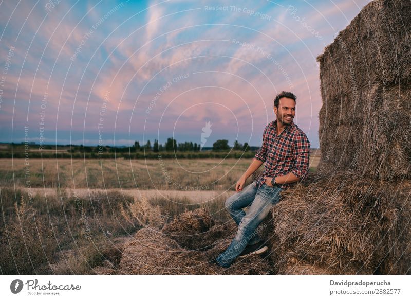 Ein glücklicher Mann sitzt auf einem Haufen Heu. Landwirt Sommer Kaukasier Landschaft Natur Länder Himmel Erholung Lifestyle Arbeit & Erwerbstätigkeit