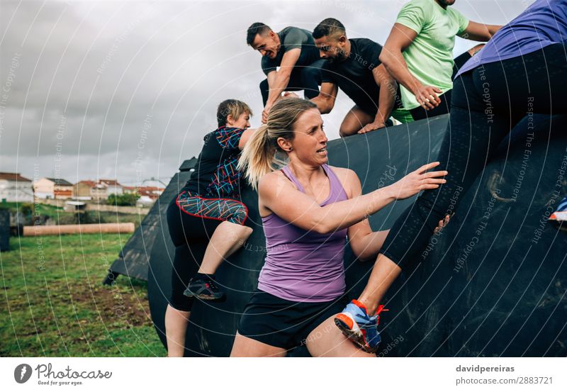 Gruppe von Teilnehmern an einem Hindernisparcours, die auf eine Trommel klettern Lifestyle Sport Klettern Bergsteigen Mensch Frau Erwachsene Mann Menschengruppe