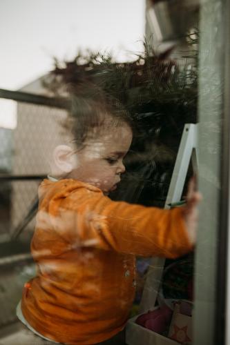 Kind durch Fenster durch Glas Isolation Quarantäne Quarantänezeit covid-19 sars-cov-2 im Innenbereich Coronavirus Prävention Pandemie Infektion Infektionsgefahr