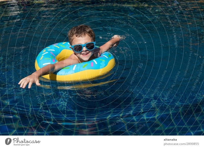 Ein kleiner glücklicher Junge, der tagsüber im Schwimmbad auf dem aufblasbaren Kreis spielt. Konzept der freundlichen Familie. Lifestyle Freude Glück Gesicht