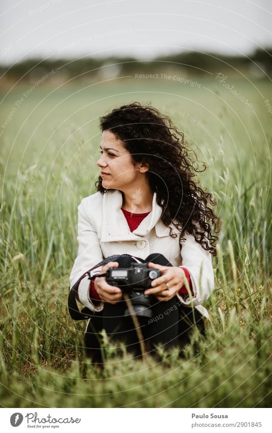 Mädchen, das mit einer Kamera auf Feldern sitzt. Lifestyle Fotografie Ferien & Urlaub & Reisen Ausflug Abenteuer Frühling Fotokamera feminin Junge Frau
