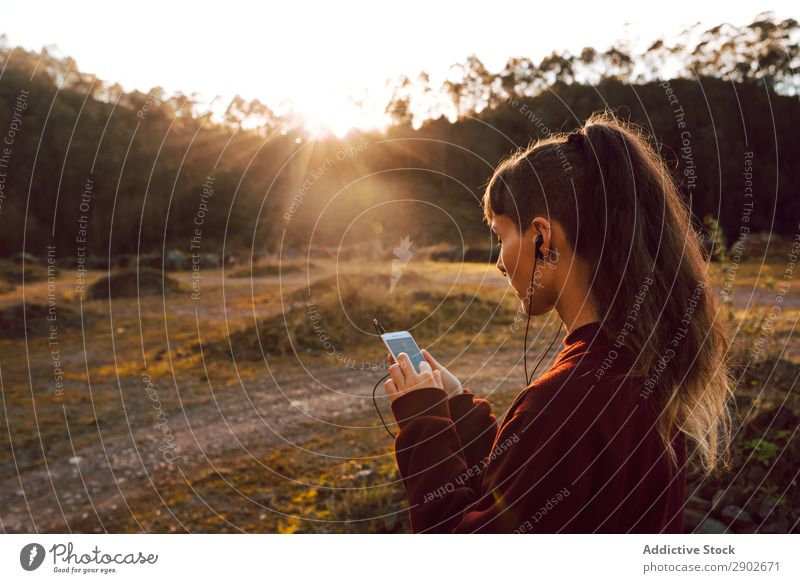 Junge Frau mit durchdringendem Musikhören auf dem Smartphone am Berg Schickimicki Kopfhörer PDA Piercing Hügel Landschaft Straße Jugendliche Handy attraktiv