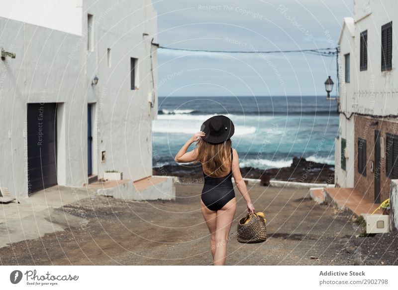 Anonyme Frau auf einer kleinen Straße der Küstenstadt Stadt Meer Küstenstreifen schäbig Lanzarote Spanien Ferien & Urlaub & Reisen Hut berühren bewundernd ruhen