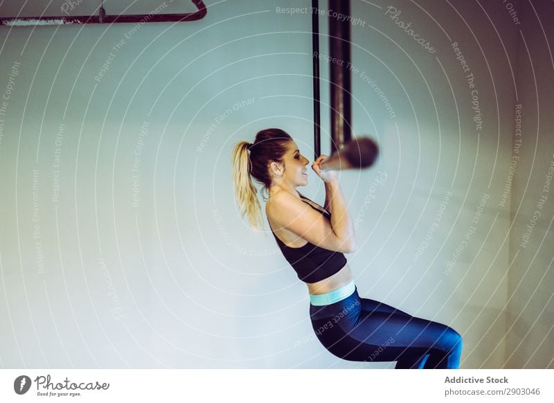 Junge Frau, die Pull-Ups im Fitnessstudio macht. Klimmzüge Bar Sporthalle aufschauend Training üben Athlet stark Gesundheit Aktion physisch muskulös
