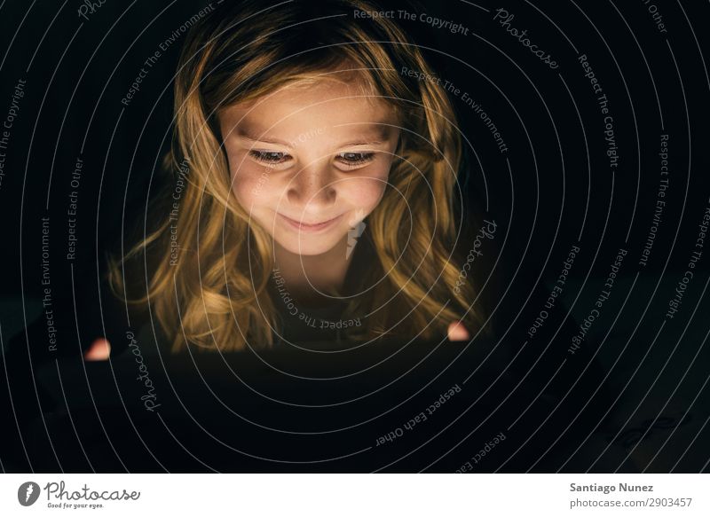Süßes blondes Mädchen, das auf einem Tablet spielt. Tablet Computer Kind Lächeln Spielen klein digital heimwärts Glück Etage Mensch Technik & Technologie Freude