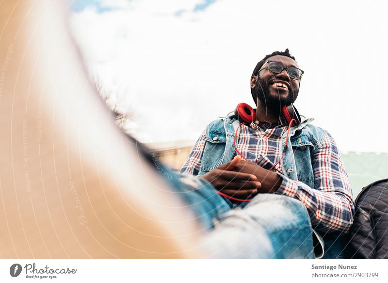 Afrikanischer junger Mann beim Musikhören. Kopfhörer Lifestyle schwarz Amerikaner Stadt Porträt Telefon PDA Mobile Solarzelle gutaussehend Technik & Technologie