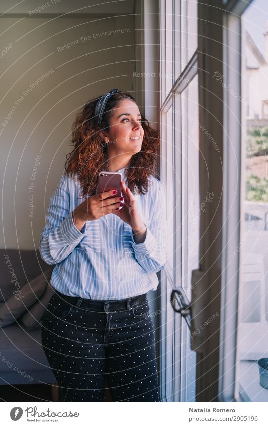 Geschäftsfrau schaut mit ihrem Handy durchs Fenster. Glück Beruf Arbeitsplatz Büro Business Unternehmen Telefon PDA Mensch Frau Erwachsene Jugendliche Lächeln