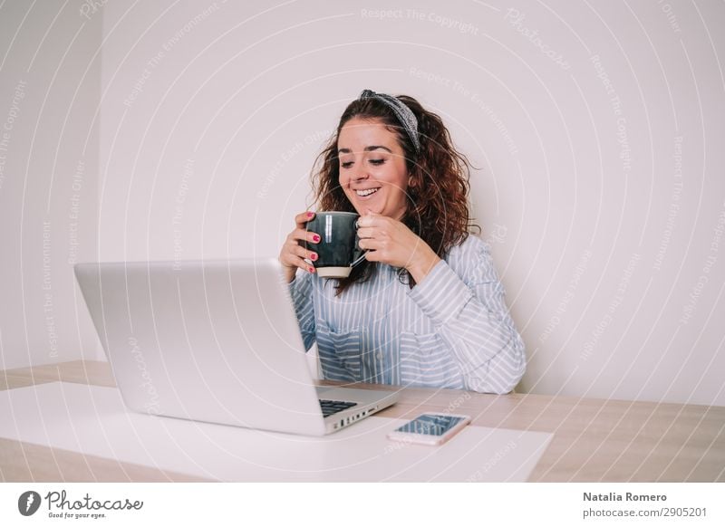 Brünette Frau benutzt ihren Computer, während sie einen Kaffee trinkt. Lifestyle Glück Schreibtisch Tisch Arbeit & Erwerbstätigkeit Büro Business Telefon
