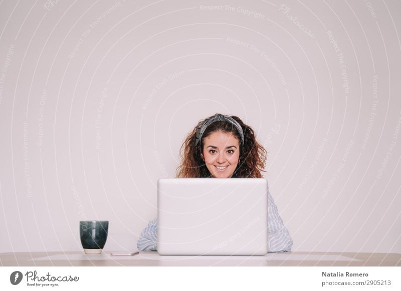 Die hübsche Frau arbeitet mit einem breiten Lächeln an ihrem Laptop. Kaffee Lifestyle Glück Schreibtisch Tisch Arbeit & Erwerbstätigkeit Büro Business Telefon