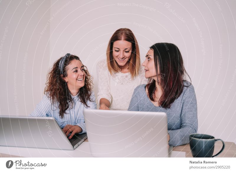 drei Frauen lachen, während sie im Büro zusammen arbeiten. Glück Schreibtisch Arbeit & Erwerbstätigkeit Beruf Arbeitsplatz Business sprechen Computer Notebook
