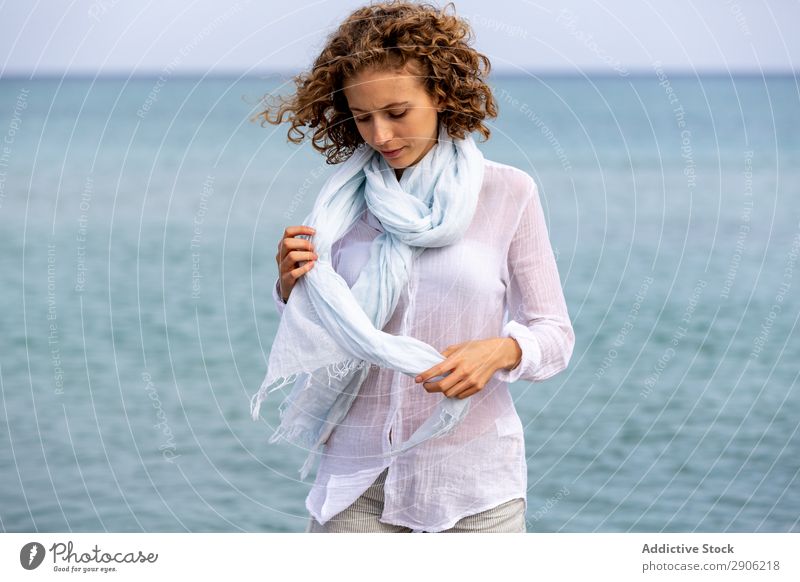 Junge Frau mit Schärpe am Wasser Schal attraktiv Oberfläche hochgezogene Hände Jugendliche charmant Lifestyle Strand lockig Haare & Frisuren ruhig Meer