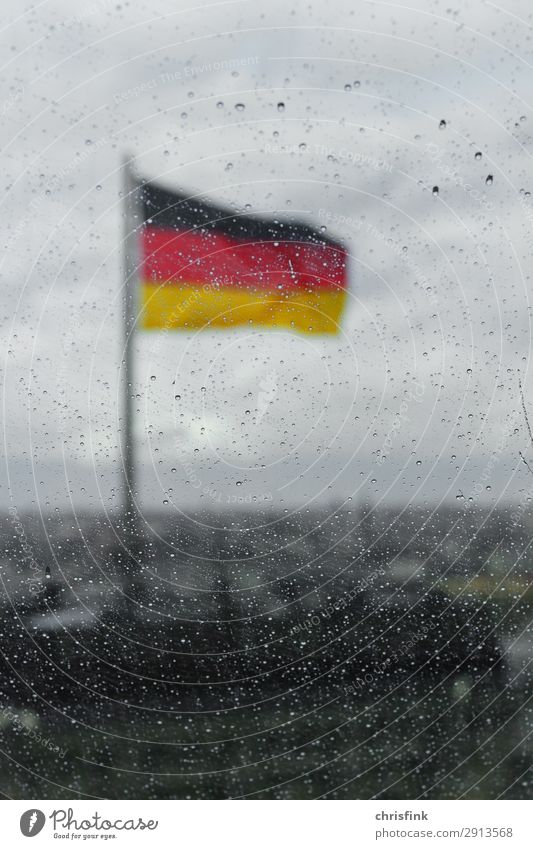 Deutsche Flagge hinter Tropfen auf Glasscheibe in Berlin Stadt Haus Gebäude Dach Zeichen Fahne kalt Regen Unschärfe Deutschland Farbfoto Abend Schatten Kontrast
