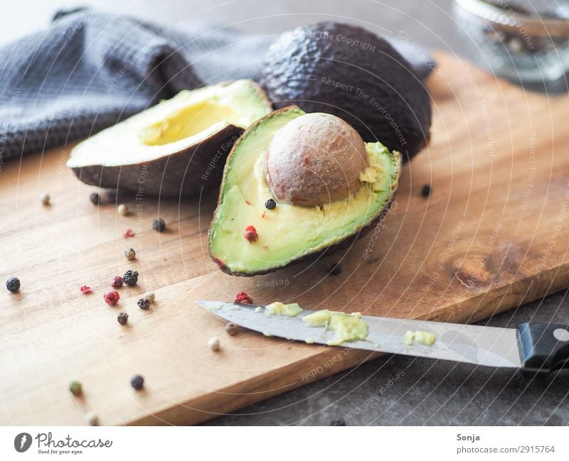 Avocado mit Kern auf einem Holzbrett Lebensmittel Gemüse Ernährung Bioprodukte Vegetarische Ernährung Diät Messer Gesunde Ernährung Schneidebrett Gesundheit