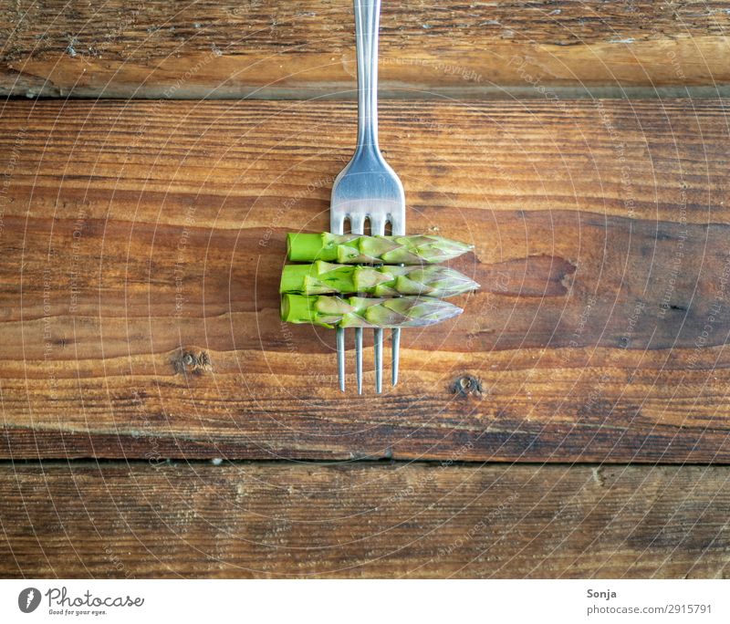 Grüner Spargel auf einer Gabel Lebensmittel Gemüse Ernährung Vegetarische Ernährung Diät Fasten Gesunde Ernährung Holztisch Gesundheit grün Frühlingsgefühle