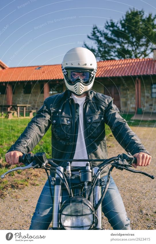 Mann mit Helm auf einem Custom-Motorrad Lifestyle Haus Mensch Erwachsene Baum Gras Verkehr Wege & Pfade Fahrzeug Mode Jeanshose authentisch retro Sicherheit