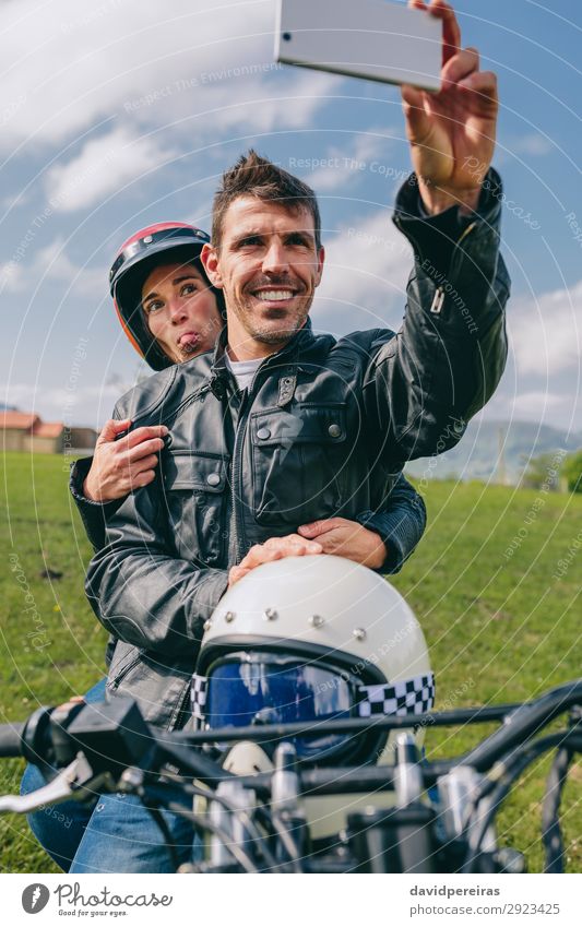 Ein Paar, das ein Selfie auf dem Motorrad macht. Lifestyle Freude Glück Ferien & Urlaub & Reisen Ausflug PDA Mensch Frau Erwachsene Mann Natur Gras Lächeln
