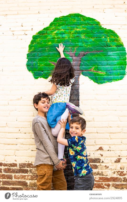 Drei Kinder spielen mit einem Baum, der an einer Wand gemalt ist. Freude Glück schön Freizeit & Hobby Spielen Freiheit Sommer Garten Klettern Bergsteigen Schule