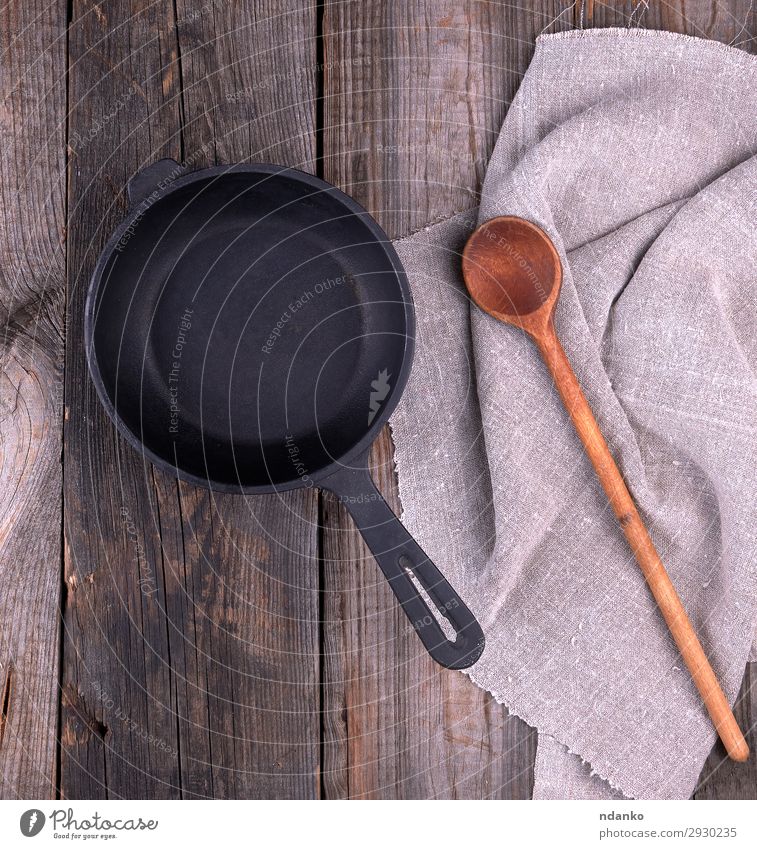 leere schwarze runde Bratpfanne mit Griff Pfanne Löffel Tisch Küche Holz Metall alt oben Sauberkeit braun grau Hintergrund Holzplatte gießen Essen zubereiten