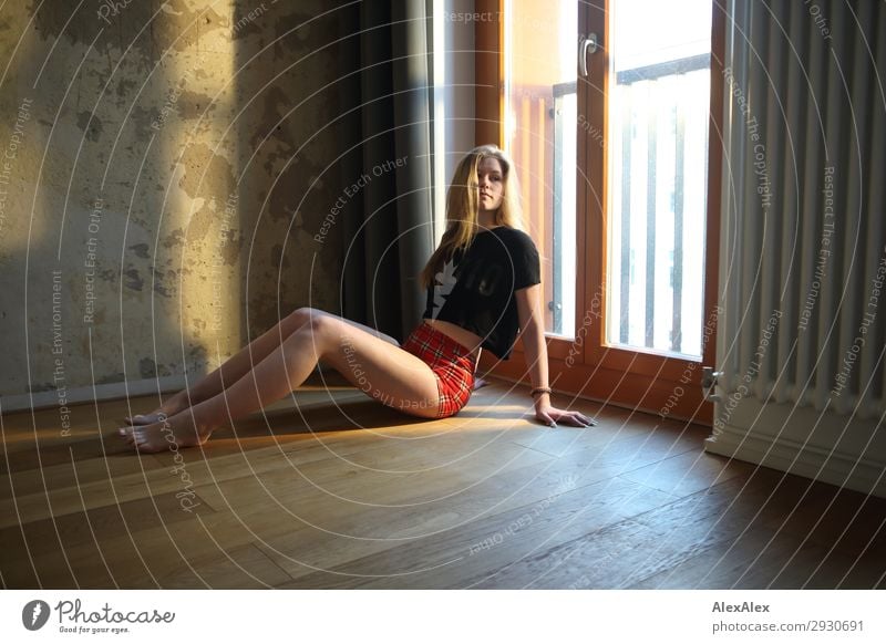 Blondes Mädchen sitzt vor einem Fenster auf dem Boden elegant Stil schön Leben Wohnung Raum Holzfußboden Junge Frau Jugendliche Beine 13-18 Jahre Schönes Wetter