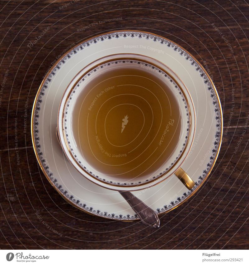 Ruhe Heißgetränk ruhig Teepflanze Warmherzigkeit Holztisch Geschirr Tasse Silberlöffel Pause Muster Goldrand gold rund Gedeckte Farben Innenaufnahme