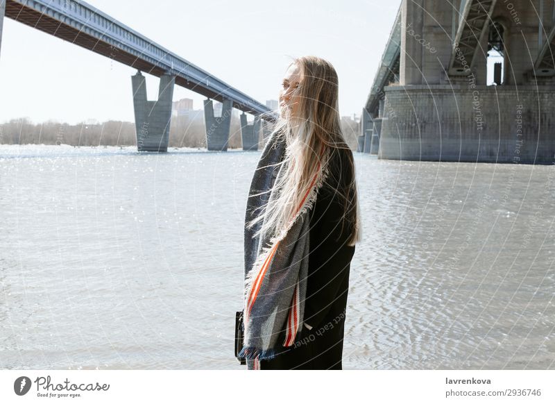 Porträt einer Frau an einem Strand mit fliegenden Haaren Ferien & Urlaub & Reisen blond Großstadt Brücke kalt Behaarung Wetter Schal Mantel Frühling Lifestyle