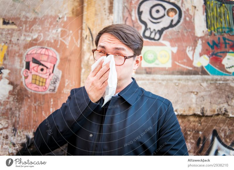 junger Mann ist krank und putzt sich die Nase Wand Porträt Junger Mann Nahaufnahme Gesicht Erkältung Krankheit Schnäuzen Taschentuch atmen Mantel