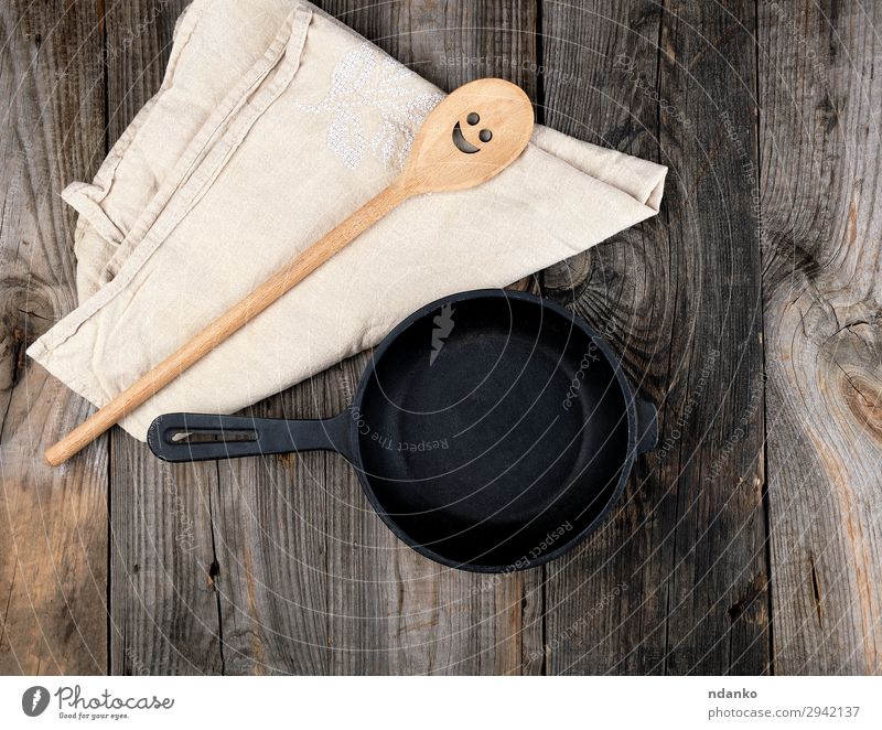 leere schwarze runde Bratpfanne Pfanne Löffel Tisch Küche Werkzeug Holz Metall alt oben Sauberkeit braun grau Hintergrund Holzplatte gießen Essen zubereiten