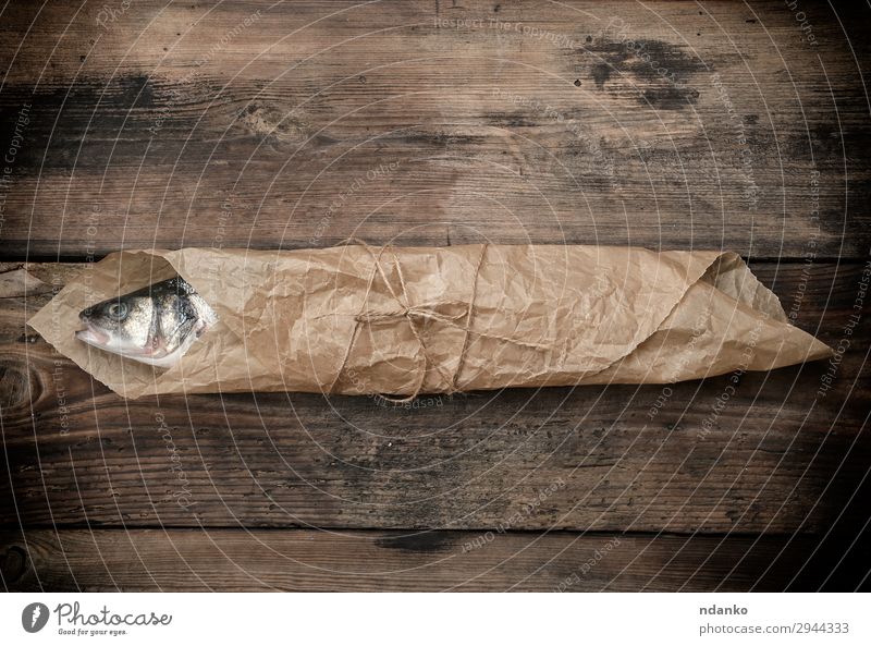 Seebarschfisch in braunem Papier eingewickelt Meeresfrüchte Ernährung Tisch Küche Seil Tier Holz Essen frisch oben grau Tasche Bass Holzplatte Essen zubereiten