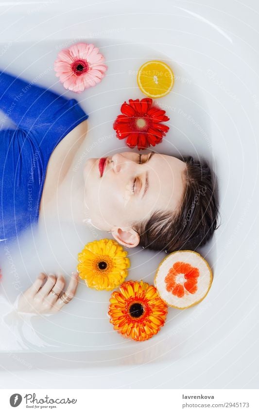 Frau, die in der Badewanne liegt, gefüllt mit Blumen und Früchten. Schwimmen & Baden schön Beautyfotografie blau Zitrusfrüchte Dekoration & Verzierung