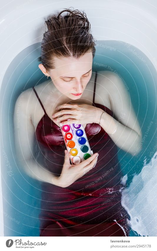 Frau in der Badewanne gefüllt mit blauen Wasser haltenden Aquarellen Künstler attraktiv Kaukasier Kreativität Kleid Gesicht heimwärts Lifestyle Farben und Lacke