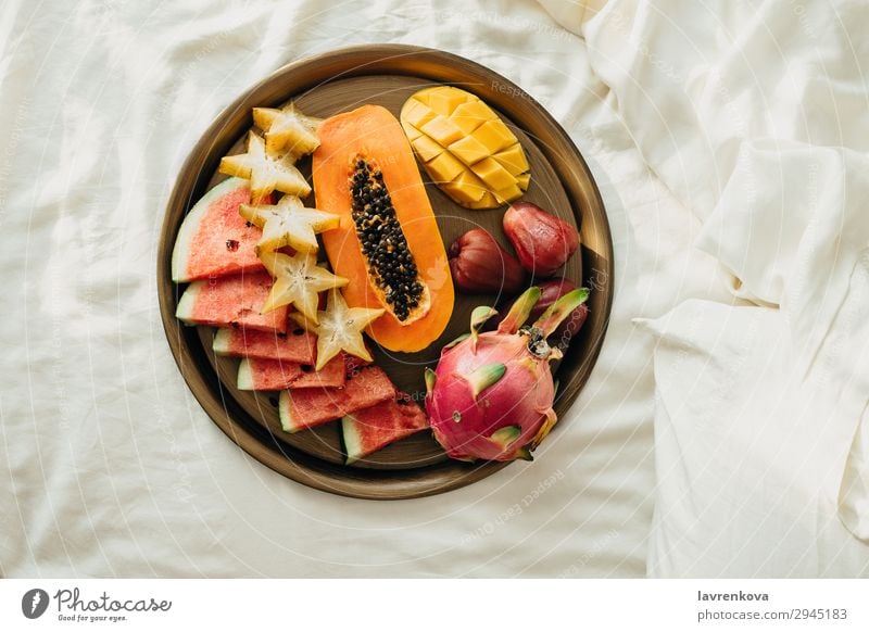 Verschiedene exotische tropische Früchte auf einem Metalltablett im Bett Schlafzimmer Frühstück Karambole geschnitten lecker Dessert Diät Drachenfrucht flach