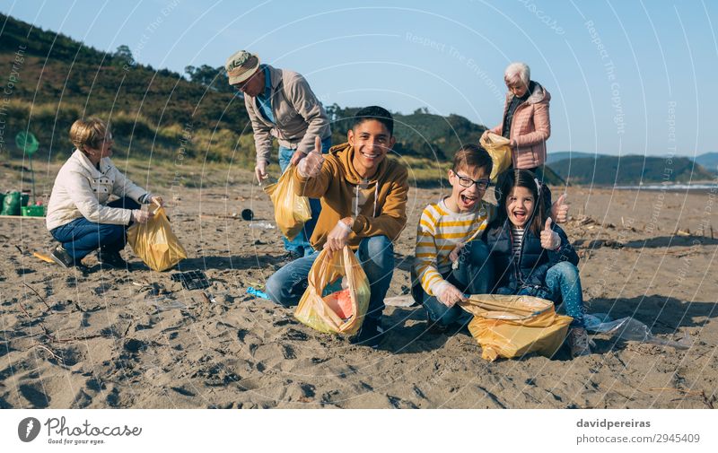 Junger Mann und Kinder reinigen den Strand Glück Mensch Erwachsene Familie & Verwandtschaft Jugendliche Menschengruppe Umwelt Sand Kunststoff Lächeln dreckig
