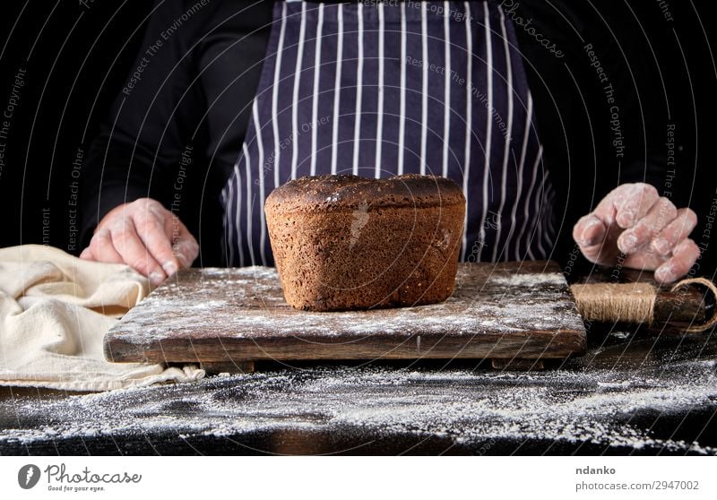 gebackenes Roggenbrot auf einem braunen Holzbrett Brot Ernährung Essen Mittagessen Abendessen Diät Tisch Küche Koch Mann Erwachsene Hand machen dunkel frisch
