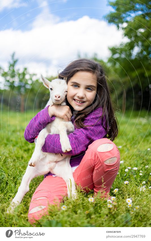 Kleines Mädchen umarmt eine Ziege auf einem Feld. Lifestyle Glück schön Freizeit & Hobby Spielen Ferien & Urlaub & Reisen Sommer Sommerurlaub Garten Kind