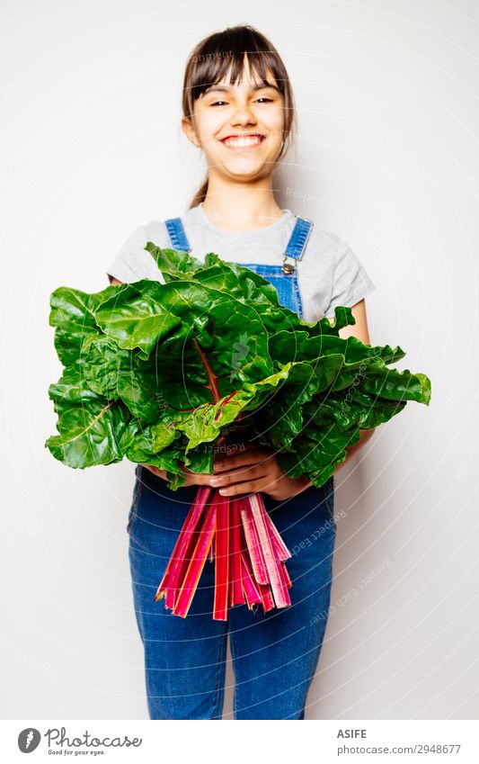 Glückliches Mädchen hält einen Haufen Mangold. Gemüse Ernährung Vegetarische Ernährung Diät Freude Kind Blatt Lächeln frisch natürlich grün rot weiß