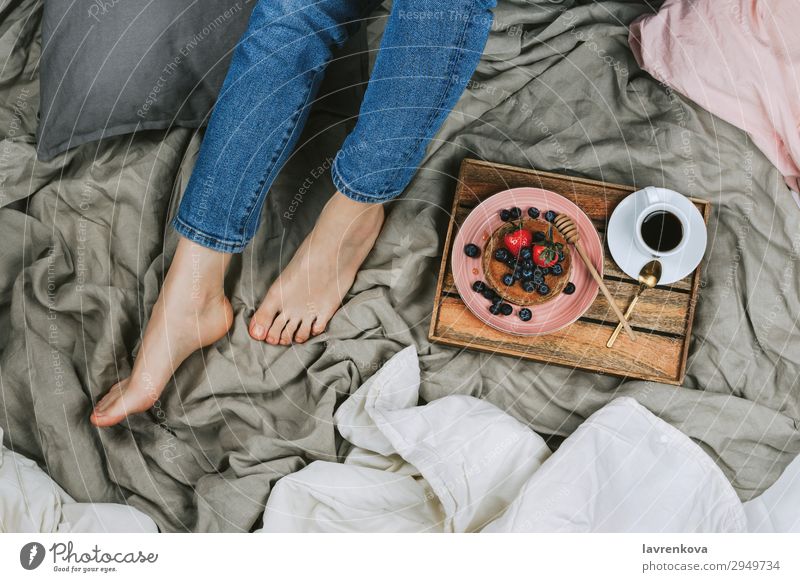 Frau auf einem Bett sitzend mit gesundem Frühstück oben Bettwäsche Schlafzimmer Blaubeeren Schalen & Schüsseln Jeansstoff Diät gesichtslos frisch Junge Frau
