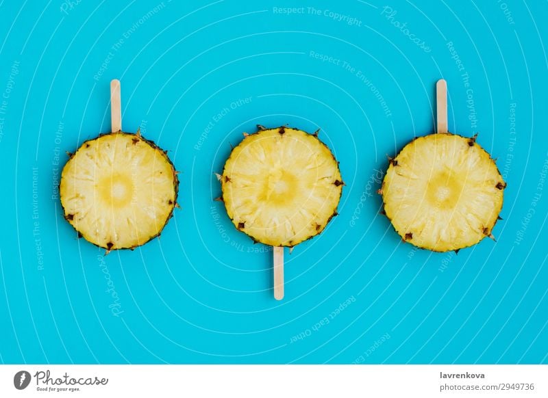 Ananaskreise auf hölzernen Eisstielen Dessert süß Bonbon Lebensmittel Gesunde Ernährung Speise Foodfotografie Stock Holz blau türkis zyan Frucht Stieleis frisch